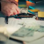 Hands counting money over papers and around papers