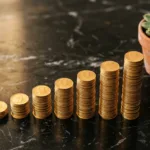 Moedas de ouro empilhadas em ordem crescente sobre superfície de mármore escuro simbolizando crescimento financeiro